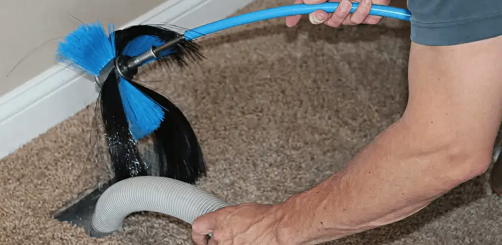 Dryer vent cleaning technician brushing lint from a vent line in Albuquerque, NM