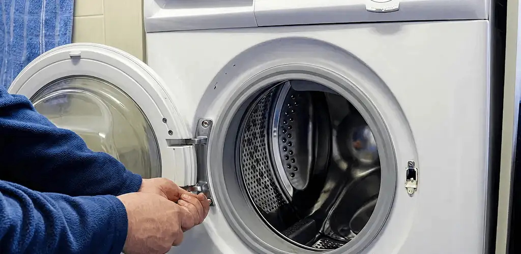 Washing machine repair handyman checking a front-load washer door and latch in Albuquerque, NM