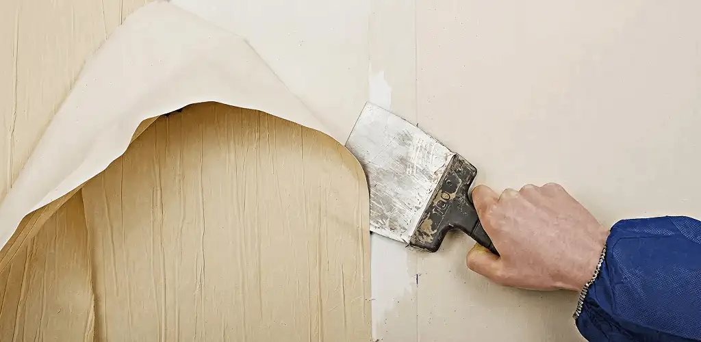 Handyman removing wallpaper with a scraper for wall preparation in Albuquerque, NM