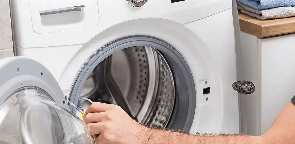 Handyman repairing a front-load washing machine and inspecting the drum in Albuquerque, NM