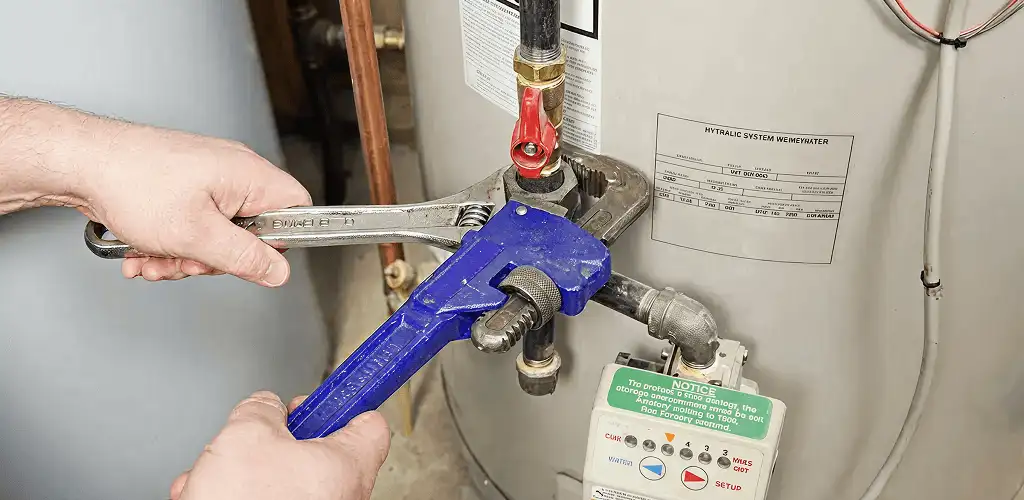 Water heater repair technician tightening the shutoff valve and supply line in Albuquerque, NM